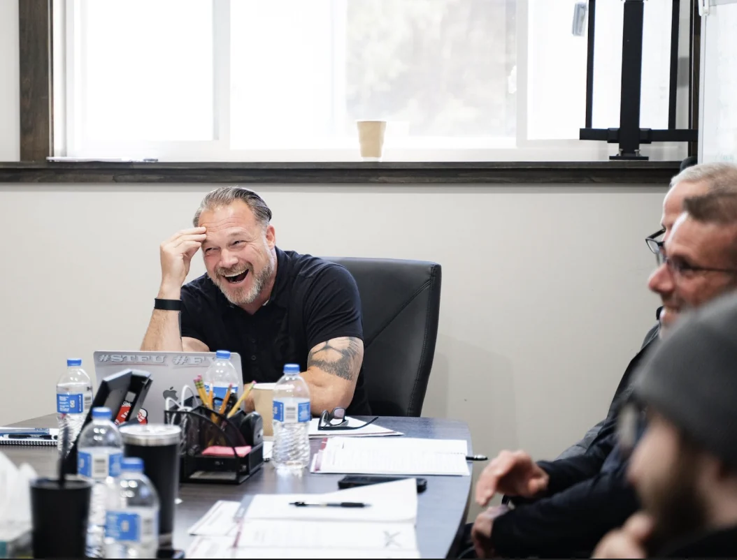 Tom laughing with contractors around a conference table
